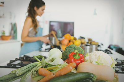 Женщина готовит, на столе лежат овощи